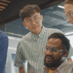 diverse group of people hovering around computer