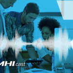 Group of people looking over a tablet with mhi cast text on it